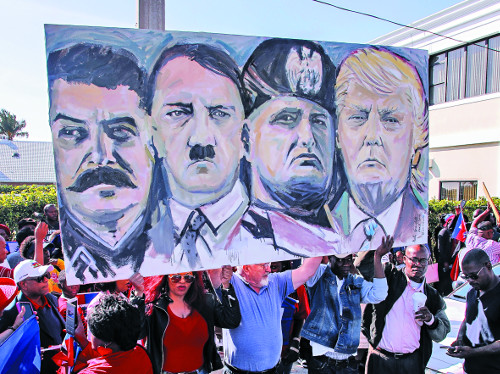 미국의 아이티계 주민들이 15일(현지시간) 플로리다주 팜비치의 도널드 트럼프 대통령 개인별장인 마러라고 리조트 근처에서 대통령을 희대의 독재자들(왼쪽부터 스탈린, 히틀러, 무솔리니)과 나란히 그린 그림을 들고 시위하고 있다. 트럼프 대통령이 지난 11일 아이티와 일부 아프리카 국가를 가리켜 ‘똥통(shithole)’이라고 표현한 것에 항의하는 시위다. 트럼프 대통령은 12일 마러라고에 와서 사흘 연속 골프를 즐겼다. AP뉴시스