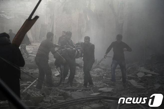 20일(현지시간) 구조대가 다친 동구타 주민을 부축하고 있다. © AFP=뉴스1