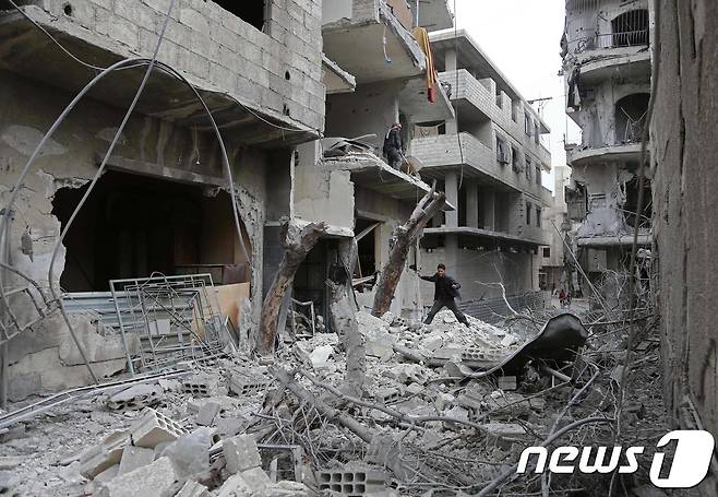 정부군 공습에 무너진 잔해를 확인하는 시리아 청소년. © AFP=뉴스1