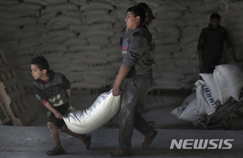 【샤티난민수용소(가자지구)= AP/뉴시스】 14일 팔레스타인 가자시티의 샤티 난민수용소에 있는 유엔 창고에서 구호식량을 배급받은 팔레스타인 사람들이 밀가루 포대를 집으로 옮겨가고 있다. 2018.1.16
