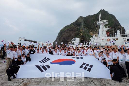 ‘제71주년 광복절 기념 독도 순례 행사’ 참가자들이 15일 오전 독도 동도에서 대형 태극기를 펼치고 기념 촬영을 하고 있다. (사진=전상희 기자)