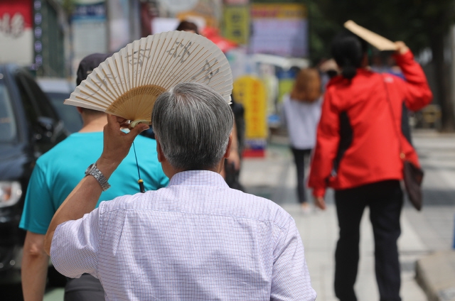 전국적으로 폭염특보가 발효된 여름날 오후 시민들이 우산과 부채 등으로 얼굴을 가리고 걷고 있다. 신소영 기자 viator@hani.co.kr