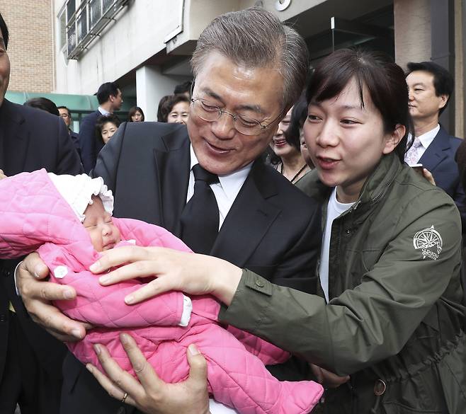 문재인 대통령이 지난해 5월10일 오전 서울시 서대문구 홍은동 자택을 나서며 생후 한 달 된 아이를 안아주고 있다. 청와대사진기자단