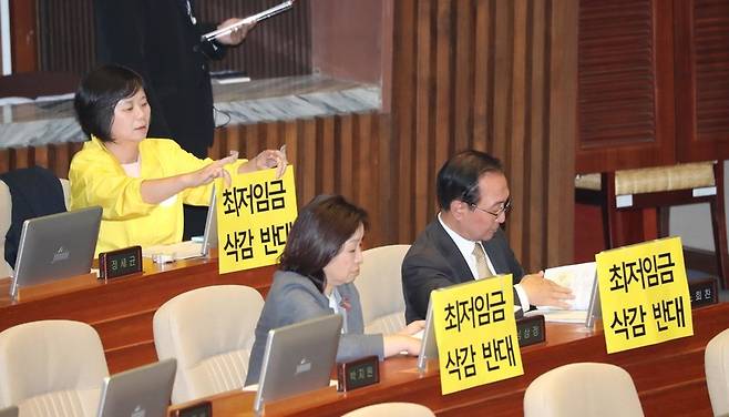 이정미 정의당 대표(왼쪽)가 28일 오후 서울 국회 본회의에서 최저임금 삭감반대 손팻말을 컴퓨터 화면 뒷면에 붙이고 있다. 강창광 기자 chang@hani.co.kr