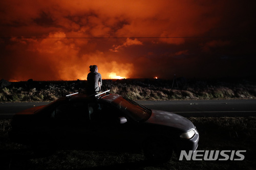 【파호아(미 하와이섬)=AP/뉴시스】미 하와이섬의 한 주민이 19일(현지시간) 갈라진 균열에서 용암이 분출되는 것을 바라보고 있다. 하와이섬에서 분출된 용암이 바다로 흘러들어가 유독가스가 발생돼 그에 따른 피해가 우려되고 있다. 2018.5.21
