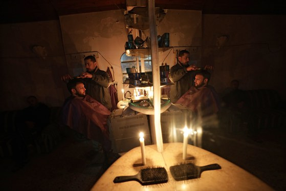 가자지구 난민촌 이발소에서 전기가 끊겨 촛불을 켠 채 머리를 자르는 모습. [EPA=연합뉴스]