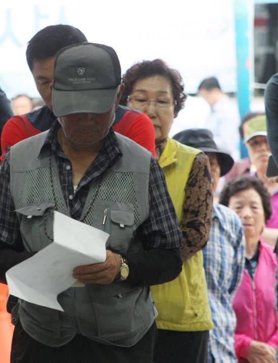 13일 오전 6시 제7회 전국동시지방선거 본투표가 시작되기 전 강원 춘천시 석사동 주민센터에 설치된 투표소 앞에서 첫 투표자인 함연복(81)씨가 투표 안내문을 읽고 있다.