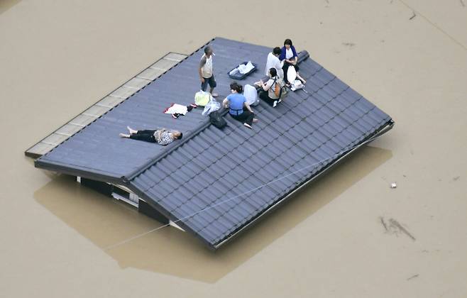 폭우로 물에 잠긴 일본 오카야마(岡山)현 구라시키(倉敷)시 마비초(眞備町) 마을에서 지붕에 대피한 주민들이 구조를 기다리고 있다. 일본 서남부 지역에는 48시간 최고 650㎜에 이르는 폭우가 쏟아졌다. 교도연합