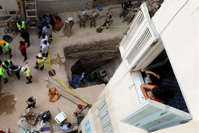 이집트 알렉산드리아의 주택가에서 19일(현지시간) 어린이 및 주민들이 오수와 섞여 있는 미라 3구가 들어 있는 석관을 발굴하고 있는 모습을 바라보고 있다.  로이터 연합뉴스
