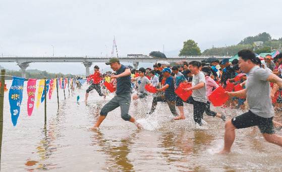재첩축제 참가자들이 섬진강에서 황금재첩을 찾기 위해 일제히 달려나가고 있다. [중앙포토]