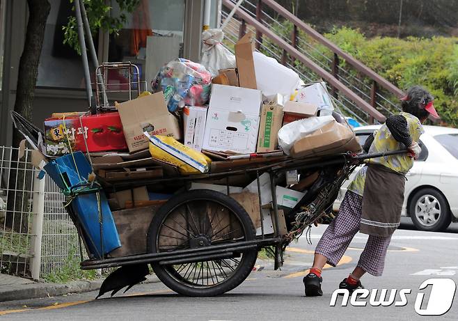 폭염이 이어지고 있는 25일 오후 서울의 한 거리에서 한 노인이 폐지가 가득 실린 손수레를 끌고 있다. 2018.7.25/뉴스1 © News1 이재명 기자