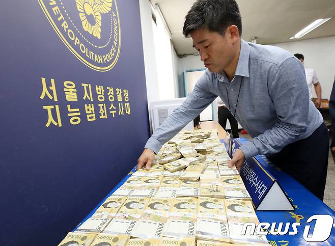 7일 서울 중랑구 서울경찰청 지능범죄수사대에서 경찰 관계자가 불법 스포츠 도박 사이트를 운영한 일당으로부터 압수한 현금을 진열하고 있다. 2018.9.7/뉴스1 © News1 구윤성 기자
