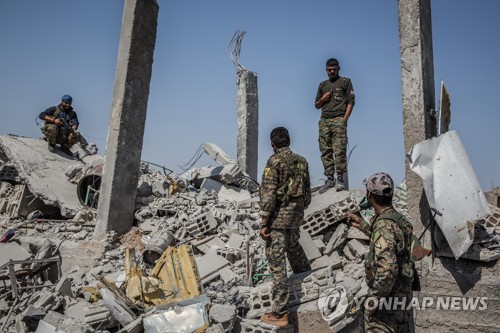 공습으로 폐허가 된 락까의 건물 잔해에 서 있는 시리아민주군(SDF) [dpa=연합뉴스 자료사진]