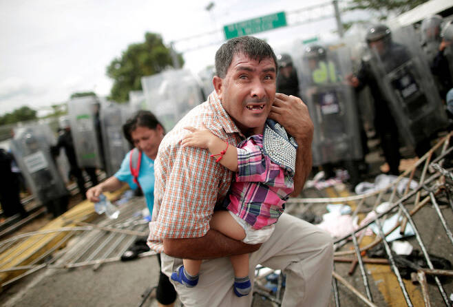 온두라스 이주민이 멕시코 국경 검문소 앞에서 자녀를 끌어안고 있다. 로이터=연합뉴스