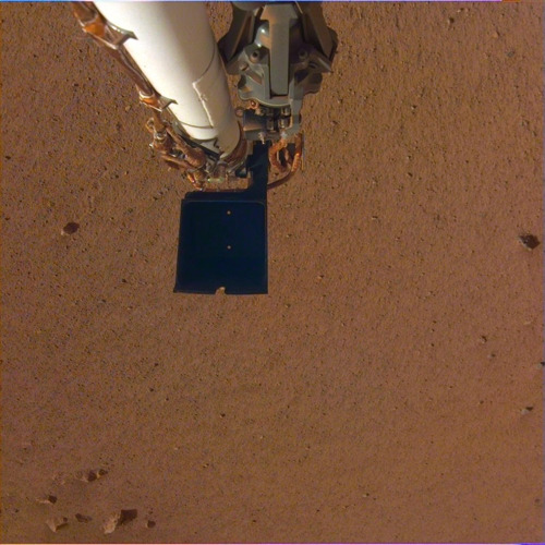 카메라에 찍힌 로봇팔과 화성 표면 로봇팔 끝의 검은 부분은 숟가락 기능을 하는 스쿠프. 그 위로 집게발이 보인다. [NASA/JPL-Caltech 제공]