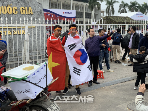 15일 하노이 미딩국립경기장 앞에서 태극기를 몸에 두른 팬이 사진을 찍고 있다.하노이 | 정다워기자