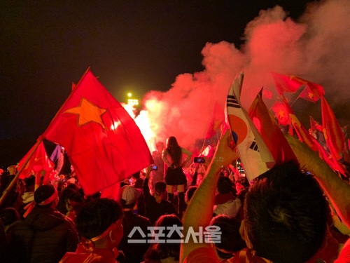 15일 미딩 국립경기장 앞에서 축구 팬이 모여 홍염을 흔들고 있다.하노이 | 정다워기자