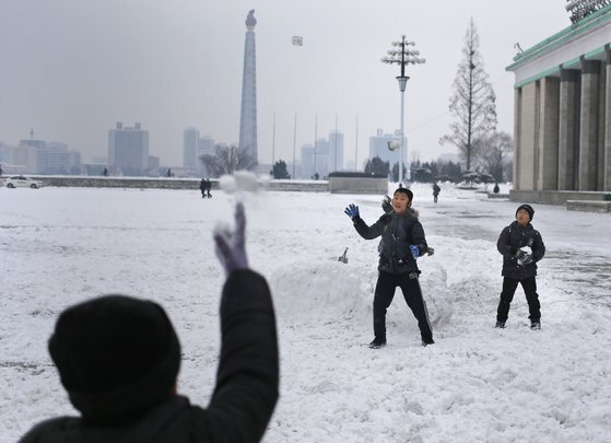 어린이들이 눈이 내린 평양 김일성 광장에서 진지를 만들고 눈싸움을 하고 있다. 뒤로 170m주체사상탑이 보인다. [AP=연합뉴스]