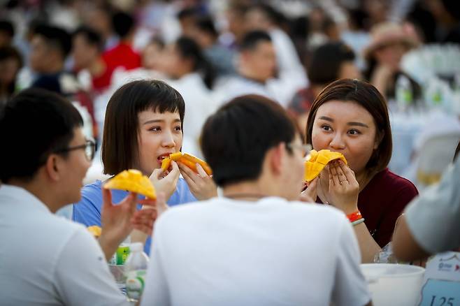 방콕을 방문한 유커들이 20일 망고를 먹고 있다. 만명의 중국관광객을 위해 4500kg의 망고가 준비됐다. 사상 최대의 망고음식을 즐긴 이날 행사는 기네스북에 기록됐다.[EPA=연합뉴스]