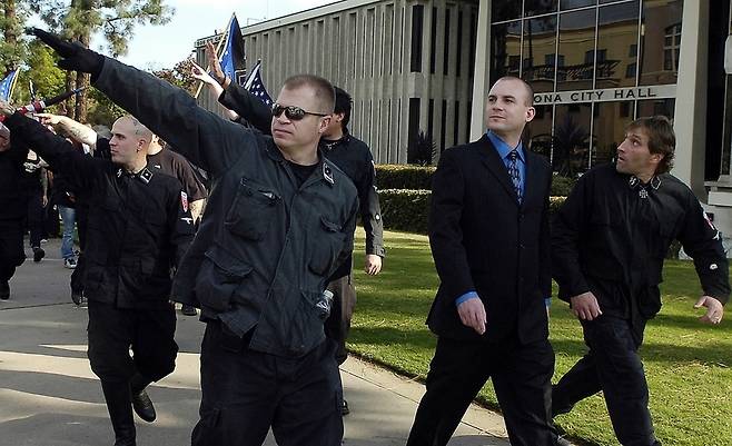 미국 네오나치 단체인 국가사회주의운동의 제프 쇼프 전 대표가 2011년 11월 캘리포니아주 포모나에서 이민자 반대 시위를 벌이면서 나치 경례를 하는 추종자들의 호위를 받으며 걷고 있다. 잭슨/AP 연합뉴스