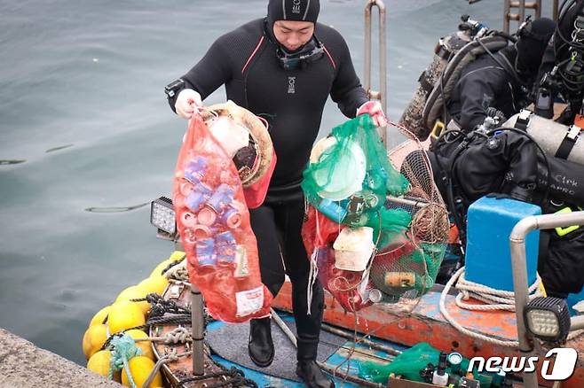 14일 서귀포시 보목동 인근 해상에서 수중정화활동을 하고 나온 다이버가 두 손 가득 쓰레기를 갖고 나오고 있다. 2019.03.17/뉴스1 © 뉴스1