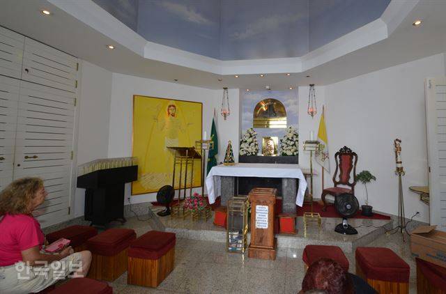 여행객이 코르코바두 언덕 구원의 예수상 기단부의 예배당에 앉아 기도하고 있다.