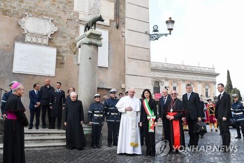 프란치스코 교황(가운데)이 26일 로마 시청을 방문해 비르지니아 라지(가운데 띠 두른 여성) 시장의 환영을 받았다. [AFP=연합뉴스]