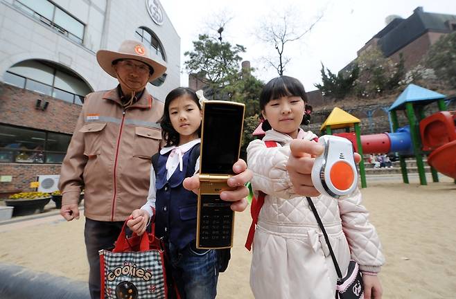 - 행정안전부는 휴대폰, 스마트폰, 전용단발기를 이용해 신속하게 112신고센터에 긴급상황과 신고자 위치를 알릴 수 있는 ‘SOS 국민안심 서비스’를 시범 실시한다고 21일 밝혔다. 서울 중구 정동 덕수초등학교에서 학생들이 휴대폰과 전용단말기를 들어보이고 있다. 2011.4.21 정연호 기자 tpgod@seoul.co.kr