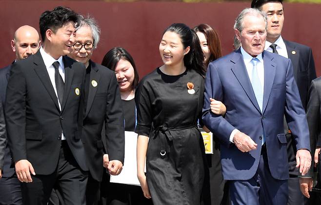 23일 오후 경남 김해시 진영읍 봉하마을에서 열린 노무현 대통령 서거 10주기 추도식에서 참배를 마친 부시 전 미국 대통령이 노 전 대통령 손녀이자 아들 건호 씨 딸과 팔짱을 끼고 이동하고 있다. 맨 왼쪽은 노 전 대통령 아들 건호 씨 (사진=연합뉴스)