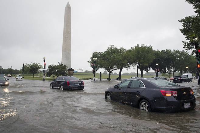 미국 워싱턴 DC 일대에 8일 오전(현지시간) 집중호우가 내렸다. 이날 워싱턴 기념탑 인근 도로가 물에 잠겨 차량이 서행하고 있다. [AP=연합뉴스]