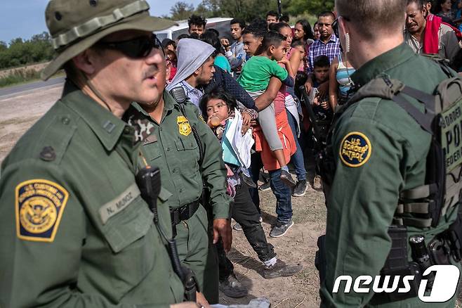 지난 7월 2일(현지시간) 미국 텍사스주 로스 에바노스에서 미국 국경수비대원들이 중미 이민자를 구금한 후 감시하고 있다. © AFP=뉴스1