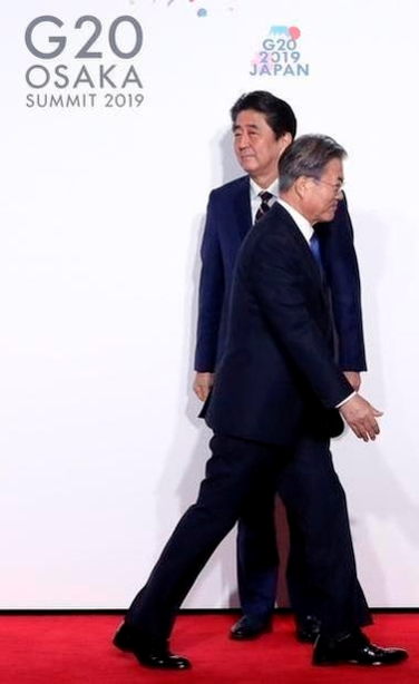 문재인 대통령과 아베 신조 일본 총리가 6월 28일 일본 오사카에서 열린 주요 20개국(G20) 정상회의 공식환영식에서 어색한 표정으로 서로를 지나치고 있다. /연합뉴스