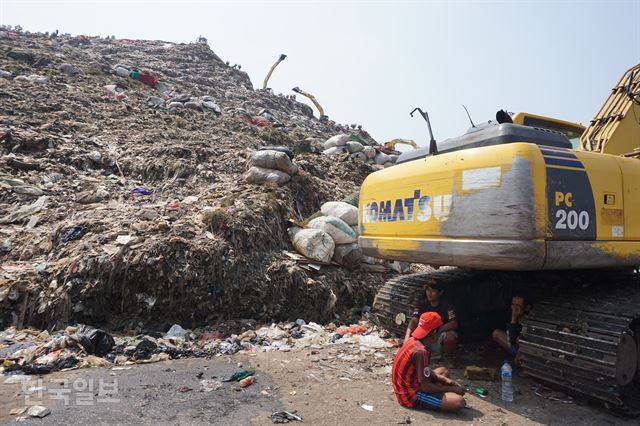 동남아 최대 쓰레기산인 인도네시아 반타르 그방 매립지에서 넝마주이들이 태양을 피해 굴착기 밑에서 쉬고 있다. 브카시=고찬유 특파원