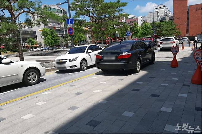 청주시가 보행환경조성사업을 추진한 용암동 용암광장. 일방통행 도로를 주차 차량이 점령한 탓에 다른 차량은 인도 위로 주행하고 있다. (사진=청주CBS 최범규 기자)
