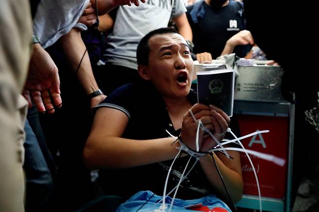 13일 밤 홍콩국제공항에서 시위대에 에워쌓인 중국 환구시보 기자 후궈하오가 손발이 묶인 채 호소하고 있다. /사진=로이터