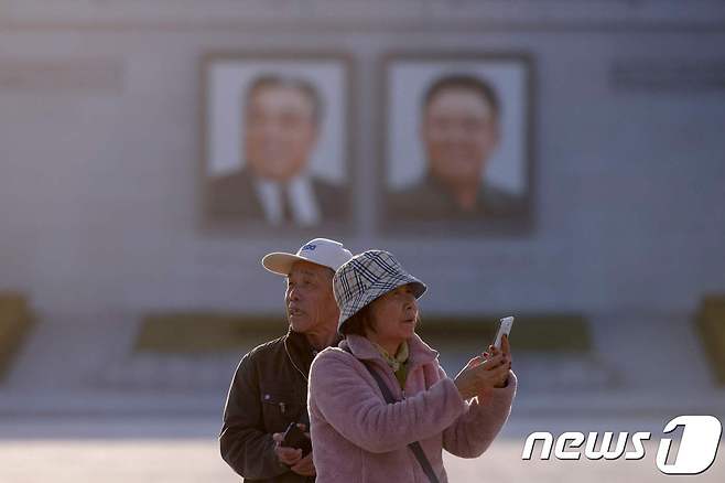 지난 4월 북한 평양시내 김일성광장에서 휴대전화로 사진을 찍고 있는 중국인 관광객들. © AFP=뉴스1