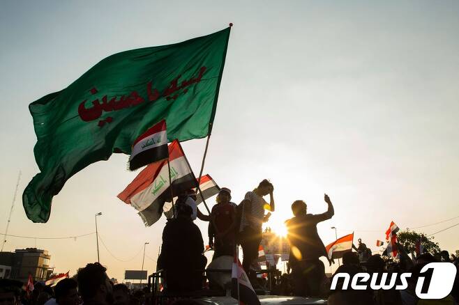 1일(현지시간) 이라크 수도 바그다드에서 이라크 국기를 든 채 시위를 벌이고 있는 반정부 시위대. © AFP=뉴스1