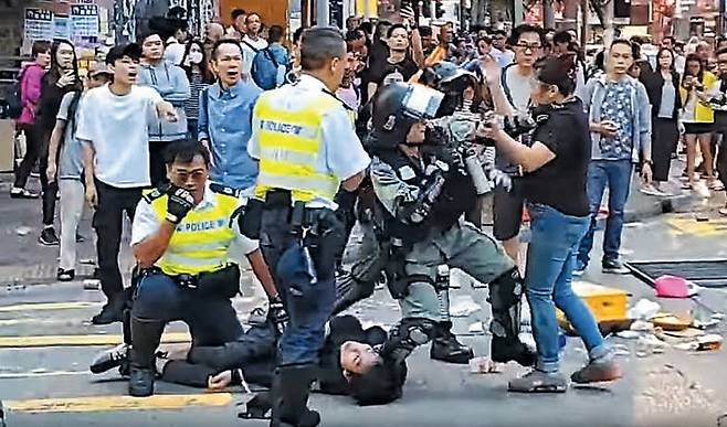 배 움켜쥐고 쓰러진 청년… 시민들, 경찰에 격렬 항의 - 홍콩 사이완호 전철역 인근에서 11일 오전 검은색 옷을 입은 시위 참가자가 경찰에게 실탄을 맞고 쓰러져 있다. 이 남성은 무기를 들지 않은 맨손으로 경찰에게 다가가다 복부에 총을 맞았고, 이후 주변에 있던 시위대와 시민들이 몰려와 실탄 발사에 대해 경찰에게 격렬하게 항의하고 있다. /유튜브