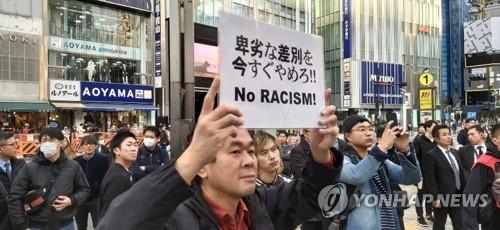 '일본의 권리를 지키는 시민 모임' 등 일본 극우 단체 회원들이 1일 오후 도쿄 신주쿠에서 한국과의 국교 단절 등을 주장하는 집회를 열고 있는 가운데 이에 반대하는 고야나기 시게루 씨가 '비열한 차별을 지금 당장 중단하라'는 내용의 손팻말을 들고 있다.