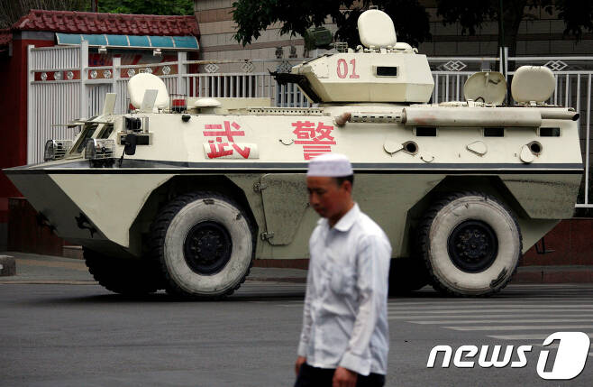 신장성의 성도인 우루무치에서 한 위구르인이 중국 무장경찰의 장갑차 앞을 지나가고 있다. 중국은 무장경찰을 배치해 위구르인의 일거수일투족을 감시하고 있다. © 로이터=뉴스1 © News1 박형기 기자