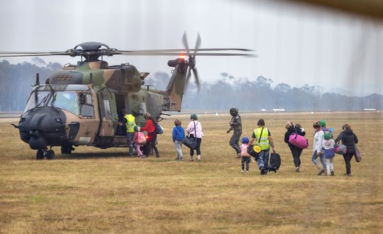 5일(현지시간) 산불이 번져 소개령이 내려진 호주의 남동부 해안도시 말라쿠타의 주민들이 구조 헬기에 오르고 있다. [AP=연합뉴스]