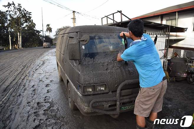 13일 필리핀 마닐라 남부 바탕가스주의 타나우안 타운에서 주민이 자동차에 쌓인 화산재를 닦고 있다. © AFP=뉴스1 © News1