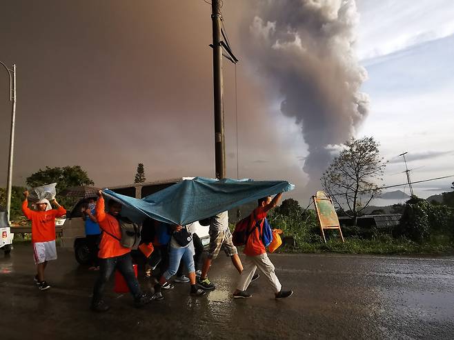 12일(현지시간) 필리핀 따가이따이 인근 지역의 따알 화산이 재를 내 뿜고 있는 가운데 주민들이 대피하고 있다. [EPA=연합뉴스]
