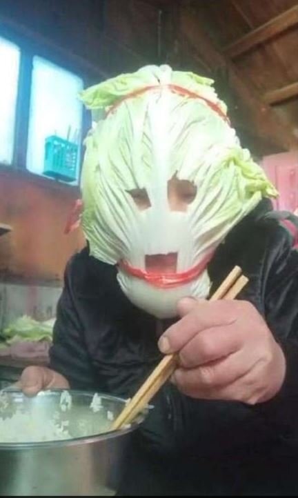 한 남성이 입과 눈 부위에 구멍을 뚫은 배추를 마스크 대신 쓴 채 식사하고 있다. [트위터 캡처]