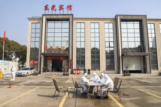 지난 3일 중국 후베이성 우한시가 격리포인트로 지정한 한 호텔 앞에 시 당국 관계자들이 앉아 있다. [AP=연합뉴스]