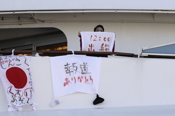신종 코로나 감염증(코로나19)가 집단 발생한 다이아몬드 프린세스호의 한 여성 승객이 지난 11일 '12시에 출발한다'고 적힌 깃발을 들어보이고 있다. [AP=연합뉴스]
