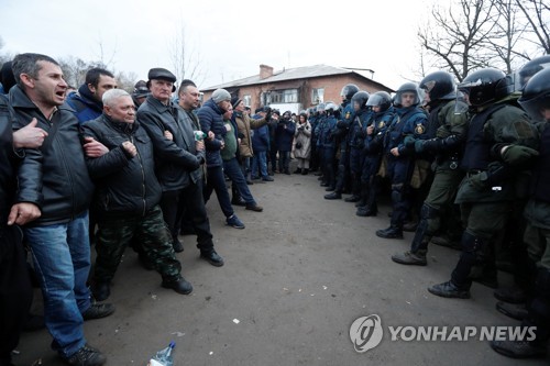20일(현지시간) 우크라이나 폴바타주 노비예 산좌리 마을의 주민들이 중국에서 이송된 72명의 격리 수용에 반대하는 시위를 벌이며 경찰과 대치하고 있다. [로이터=연합뉴스]