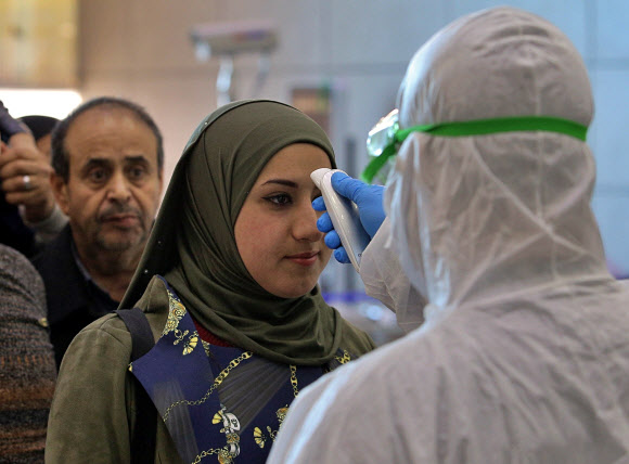 이란을 떠난 항공기 편으로 이라크 나자프 공항에 도착한 여행객들이 21일(현지시간) 응급 의료요원으로부터 체온을 점검받고 있다.나자프 AP 연합뉴스
