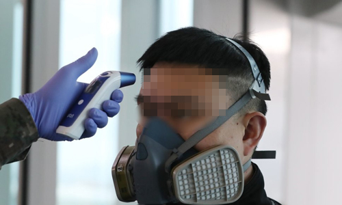 신종 코로나바이러스 감염증인 '우한 폐렴' 공포가 확산하는 가운데 지난 1월28일 부산 강서구 김해공항 입국장에서 중국발 항공기에서 내린 한 중국인 승객이 방독면을 착용하고 발열 검사를 받고 있다.