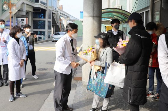 서영성 대구동산병원장이 완치 판정을 받고 퇴원하는 '코로나19' 확진자 3명에게 꽃다발을 전달하고 건강을 기원했다. 사진=동산병원 제공